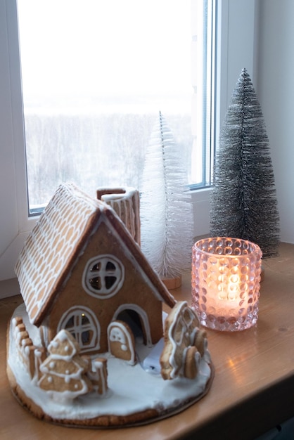 Foto kersthuis gemaakt van gemberkoekjes met peperkoekauto buiten versierd in kerstsfeer