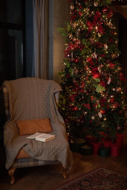 Kerstinterieur met fauteuil en dennenboom Een fauteuir staat naast een versierde kerstboom