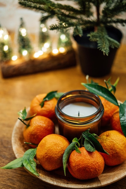 Kerstkaarsen voor de feestdagen citruskaars en sappige sinaasappelen op nieuwe houten keukentafel