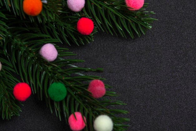 Kerstkaart. Flatley-takken van een kerstboom met kleurrijk bontspeelgoed op een zwarte achtergrond.