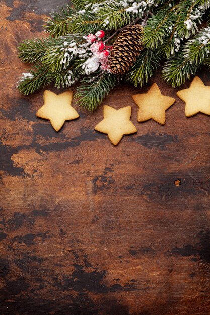 Foto kerstkaart met peperkoekjes en dennenboom op houten achtergrond boven uitzicht met ruimte voor uw groeten flat lay