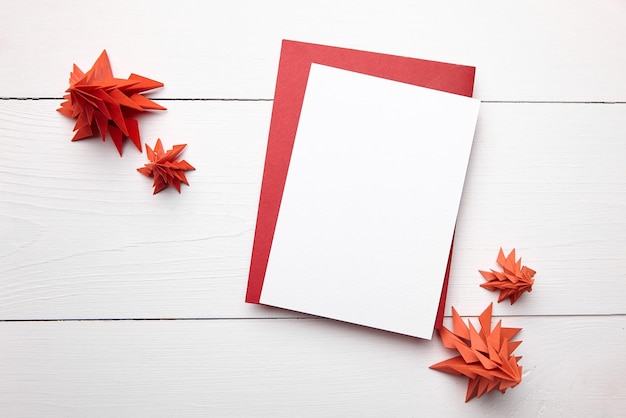 Kerstkaart mockup met envelop en rode papieren sparren op witte houten achtergrond bovenaanzicht plat leggen