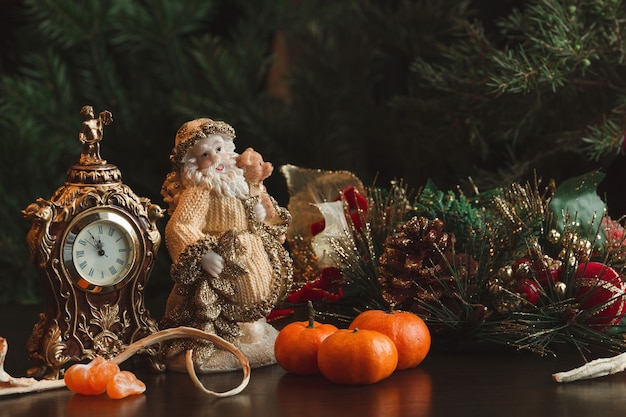 Kerstkaart. nieuwjaar. samenstelling klok, mandarijnen, kerstman op de achtergrond van dennentakken