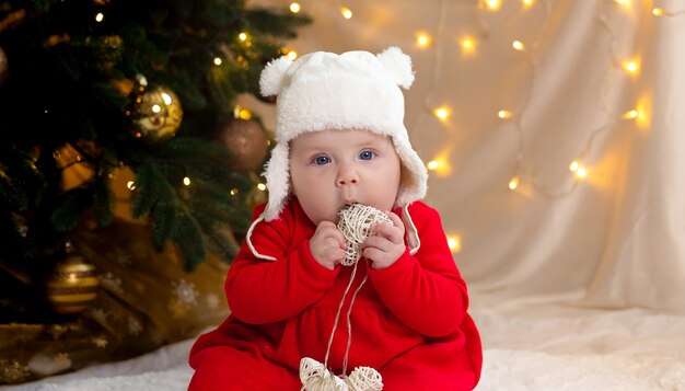 Kerstkind dat naar de camera kijkt en een slinger met harten houdt.