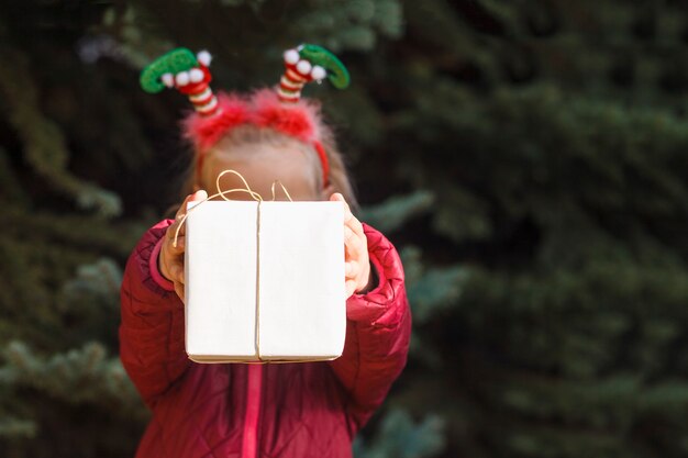 Kerstkind houdt een geschenkdoos voor haar gezicht