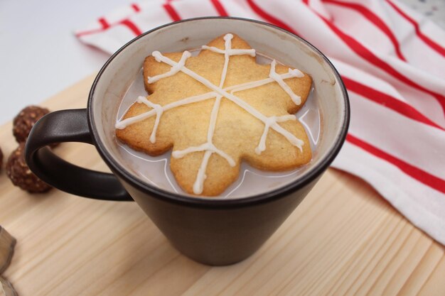 Kerstkoekje in de vorm van een sneeuwvlok op een donkerbruine kop koffie of melk met chocolade