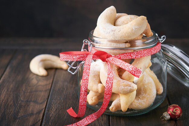 Kerstkoekjes halve manen Zelfgemaakte traditionele kerstkoekjes shortbread halve manen in pot bestrooid met poedersuiker op oude houten achtergrond Duitse en Oostenrijkse traditionele kerstkoekjes