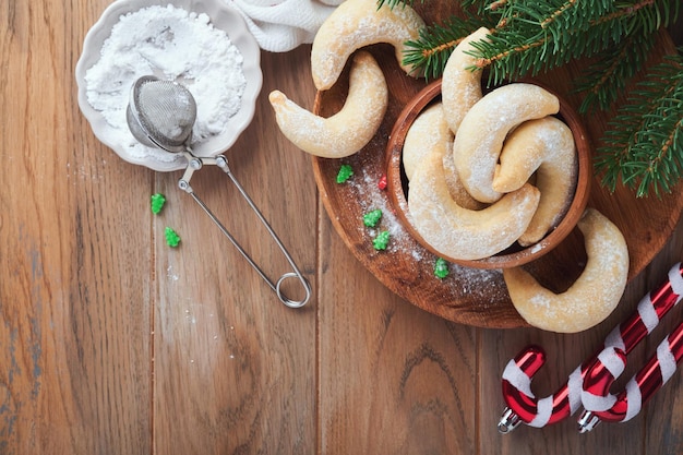 Kerstkoekjes halve manen Zelfgemaakte traditionele kerstkoekjes Vanille halve manen in rustieke plaat met kerstversieringen op oude houten rustieke achtergrond Voedselpatroon Vakantie bakken concept