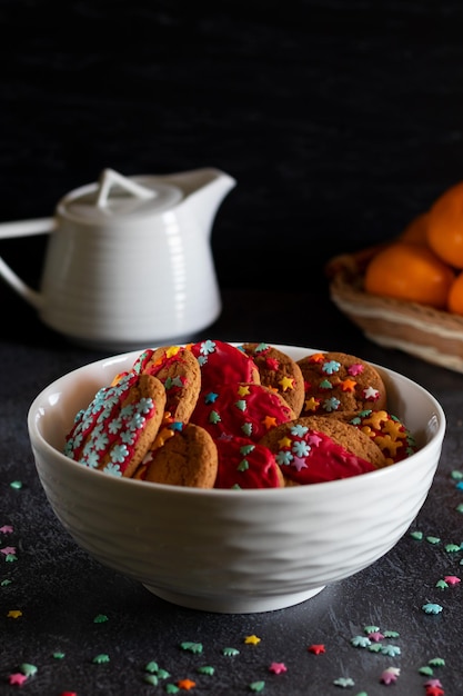 Foto kerstkoekjes mandarijnen en een witte theepot op een donkere achtergrond