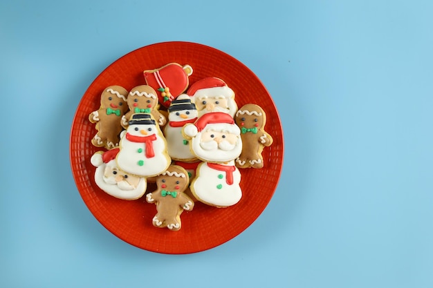 Kerstkoekjes met de vorm van een kerstman, sneeuwman en gemberman geserveerd in de rode plaat.