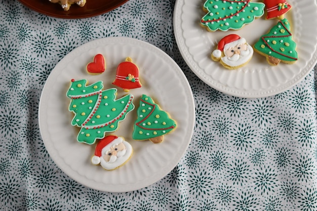 Kerstkoekjes met kerstboom vorm geserveerd in witte plaat met witte achtergrond.