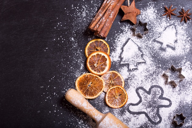 Kerstkokende dennenboom gemaakt van meel op een donkere tafel ingrediënten voor het bakken en gedroogd fruit