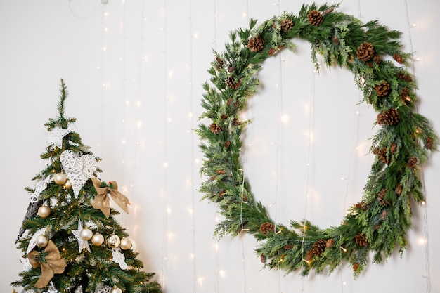 Kerstkrans met takken van een kerstboom aan de muur. Nieuwjaarsdecor in een gezellig huis