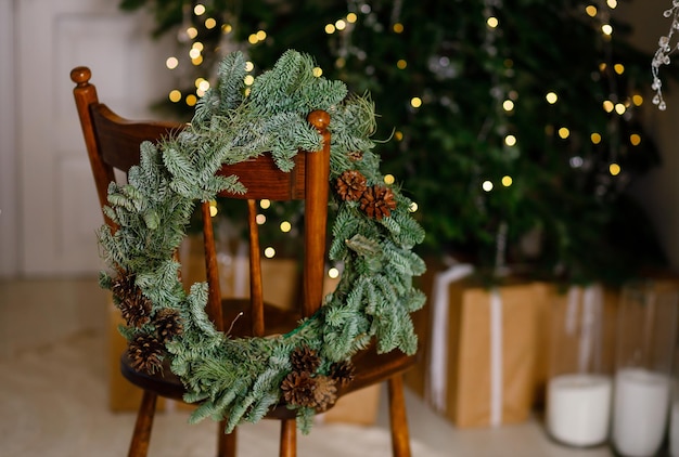 Kerstkrans op een stoel thuis op de achtergrond van een groene kerstboom Nieuwjaarsverhalen
