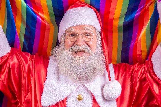 Kerstman die bedekt met lgbt-trotsvlag. zelf. een. je vuist omhoog houden, de lgbt-vlag bedekken. lgbt + vlag op rode achtergrond. kerstmis.