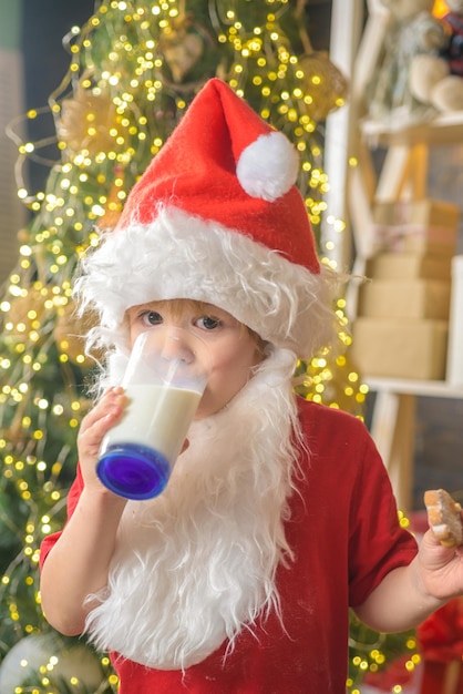Kerstman die koekjes eet en melk drinkt op kerstavond Gelukkige kerstman die een koekje eet en