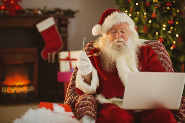 Kerstman die laptop op de leunstoel met behulp van