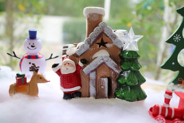 Kerstman en houten huis met kerstboom, rendieren met rode geschenkdoos en sneeuwpop.