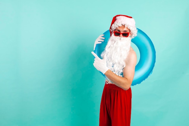 Kerstman in pak met opblaasbare zwemring in zonnebril rust op het strand en punten