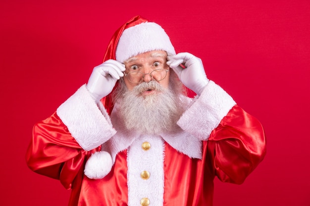 Kerstman kijken naar de camera. Kerst komt eraan. Vrolijk Kerstfeest. De kerstman kijkt toe. Hij houdt zijn bril vast.