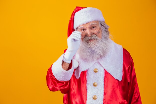 Kerstman kijken naar de camera. Kerst komt eraan. Vrolijk Kerstfeest. De kerstman kijkt toe. Hij houdt zijn bril vast.