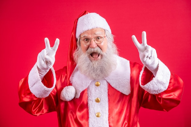 Kerstman kijken naar de camera. kerst komt eraan. vrolijk kerstfeest. vrede. v-teken.