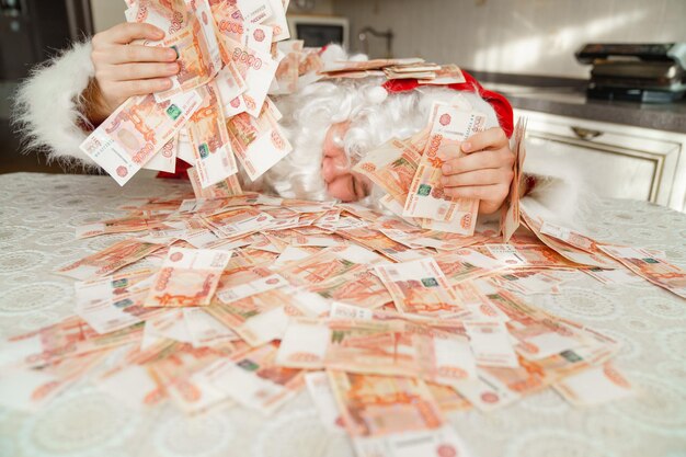 Foto kerstman liggend in het geld op tafel