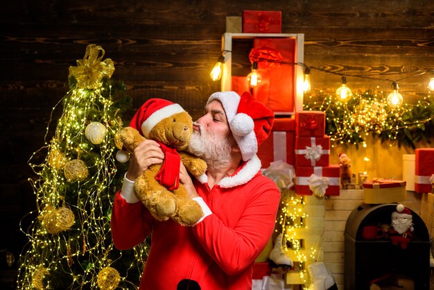 Kerstman man kussen teddybeer bebaarde man in kerstman kostuum Kerstman houdt teddybeer vast