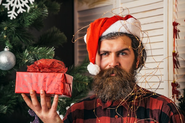 Kerstman man met huidige doos bij kerstboom
