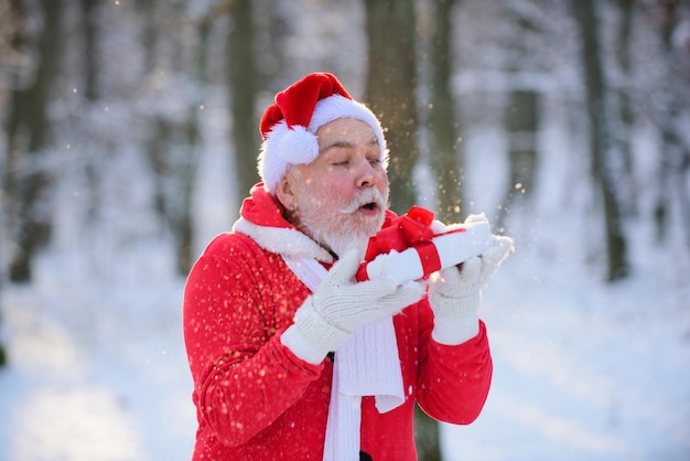 Kerstman met cadeau in het sneeuwbos