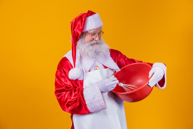 Kerstman met een kom die cake op gele achtergrond slaat