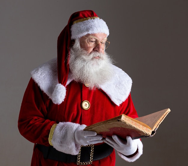 Kerstman met een oud rood omslagboek. Namen opschrijven cadeaus voor Kerstmis. Kerst komt eraan