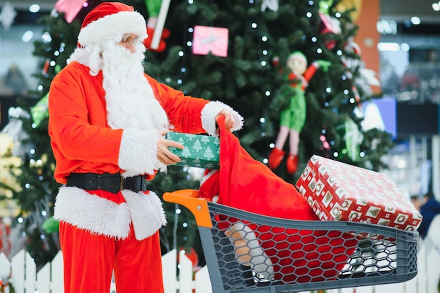 Kerstman met geschenken in een winkelwagentje in het winkelcentrum.