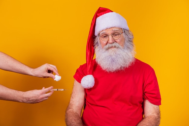 Kerstman met gezichtsmasker wordt gevaccineerd met injectie