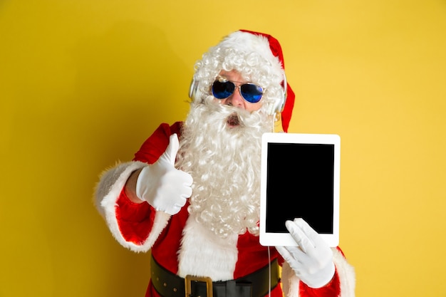 Kerstman met moderne bril geïsoleerd op gele studio achtergrond