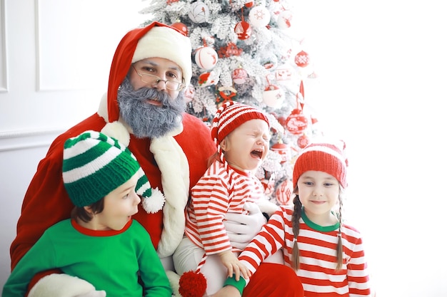 Kerstman zit met kleine schattige elfjes op kerstachtergrond Tijd van wonderen Geschenken van de kerstman