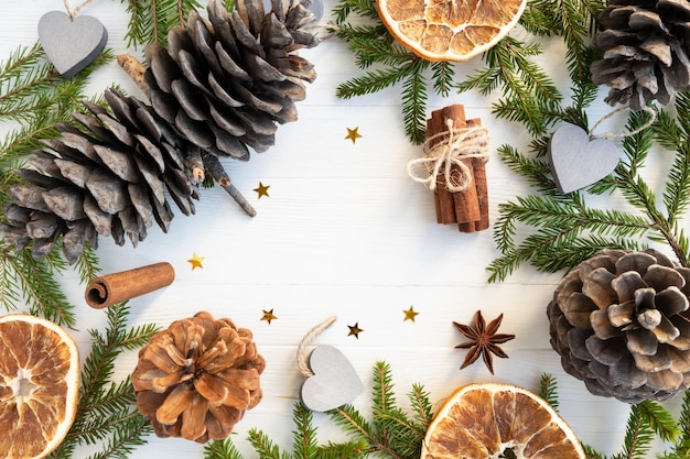 Kerstmis achtergrond kerstboom takken dennenappels kaneel steranijs oranje chips op een witte achtergrond met ruimte voor tekst lay-out van een briefkaart poster