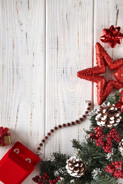 Kerstmis achtergrond. Witte houten planken met dennentakken, dennenappels, rode geschenkdoos.