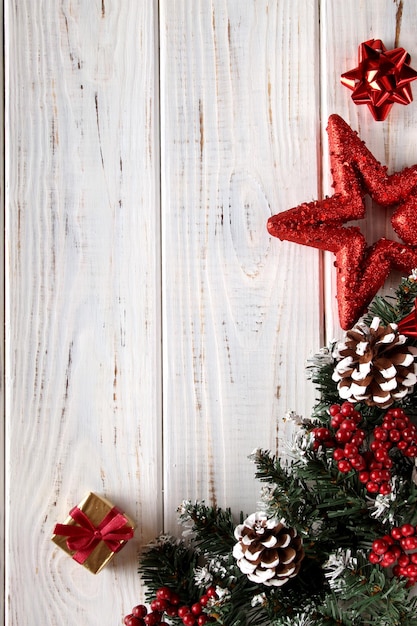 Kerstmis achtergrond. Witte houten planken met dennentakken, dennenappels, sneeuw, rode ster en rode bessen.
