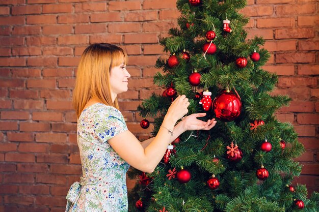 kerstmis, decoratie, vakantie en mensenconcept - vrouw versieren kerstboom