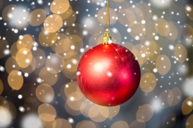 Foto kerstmis, decoratie, vakantieconcept - sluit omhoog van rode glanzende bal over gouden lichtenachtergrond