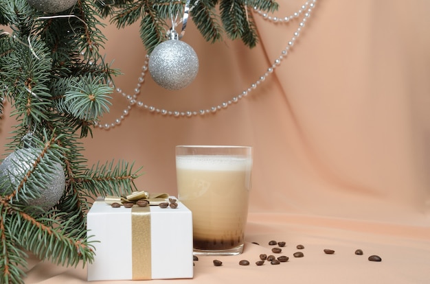 Kerstmis. Een nieuwjaarscompositie gemaakt van takken van een kerstboom, een geschenkdoos, een glazen mok met koffie en melk. Selectieve aandacht.