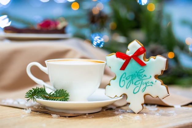 Kerstmis en gelukkig nieuwjaarskaart met kopje koffie, pijnbomen, fir tak en peperkoek op houten tafel