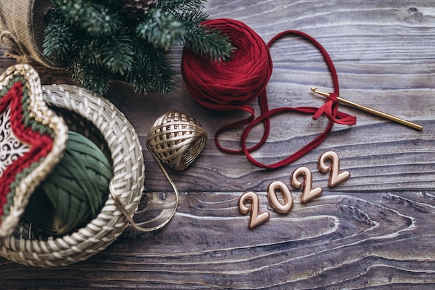 Kerstmis en Nieuwjaar 2022 wenskaart, ballen van gebreid garen, haaknaald en gebreide mand op een houten tafel, bovenaanzicht