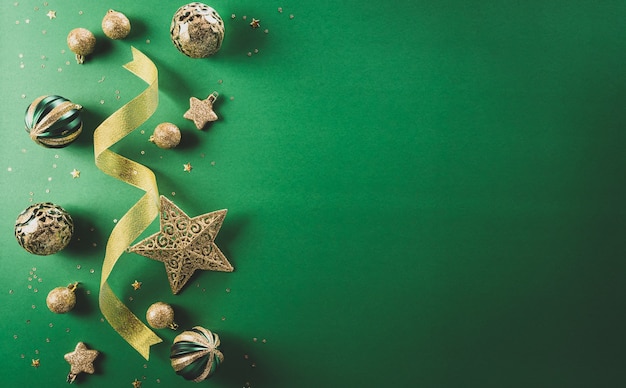 Kerstmis en Nieuwjaar achtergrond concept. Bovenaanzicht van gouden lint, kerstbal, ster en sneeuwvlok op groene achtergrond.