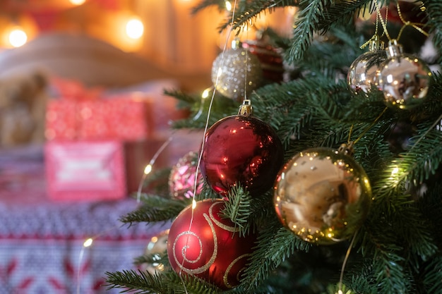 Kerstmis en oudejaarsavond dennenboom met ornamenten decoratie van rode en gouden ballen met geschenkdozen op de achtergrond