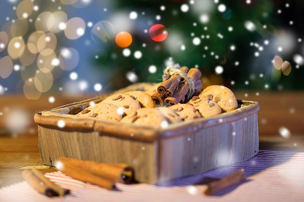 Kerstmis, feestdagen, eten en bakken concept - close-up van haverkoekjes in houten kist en kaneel op tafel boven lichten