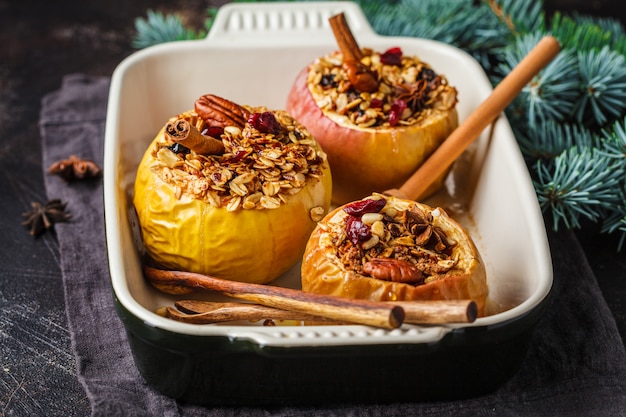 Kerstmis gebakken appelen met granola, Amerikaanse veenbessen, noten en honing in de ovenschotel, donkere achtergrond.