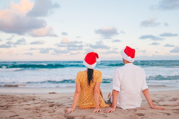 Kerstmis gelukkig paar in kerstmanhoeden op strandvakantie