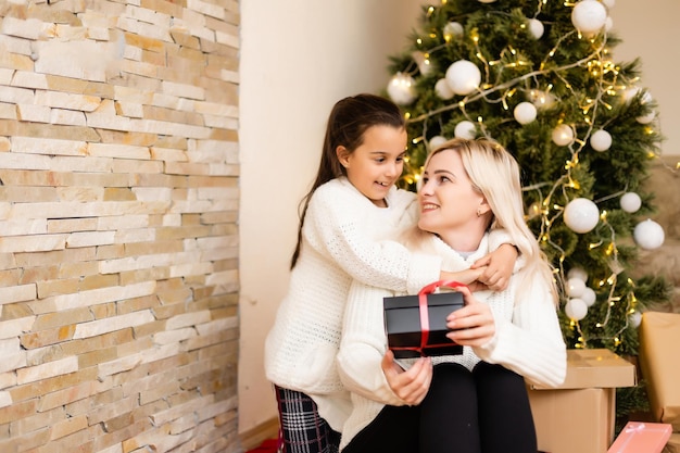 Kerstmis, gelukkige familie moeder met dochter met cadeaus op kerstavond